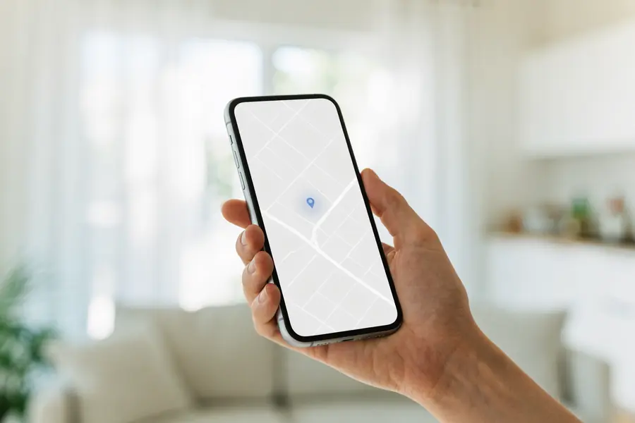A hand holding a smartphone showing a map with a location pin